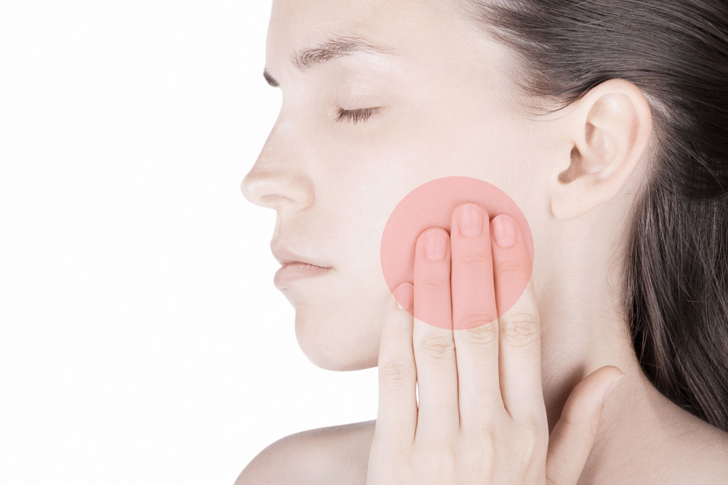 woman holding sore jaw